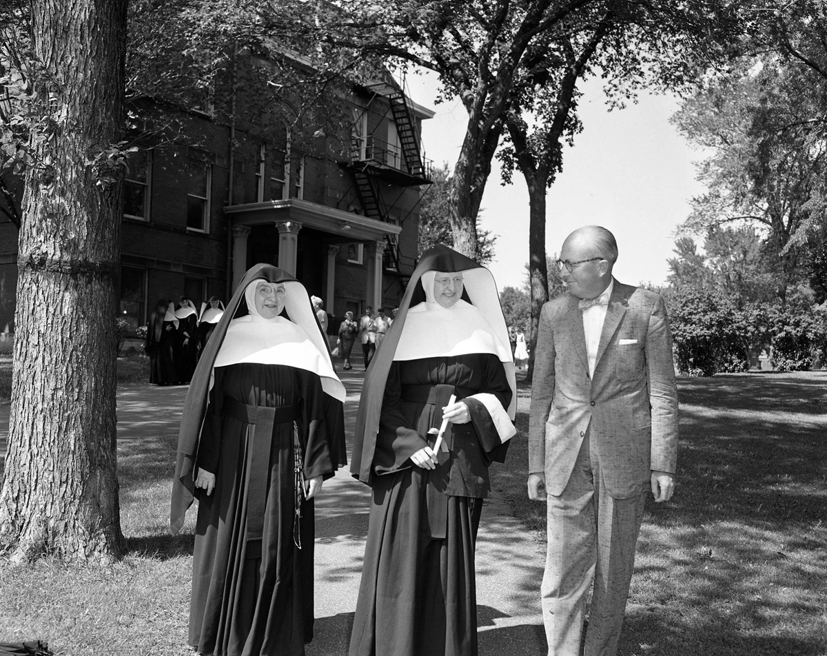 Photo of Sr. Maria Lamm walking with colleagues on campus